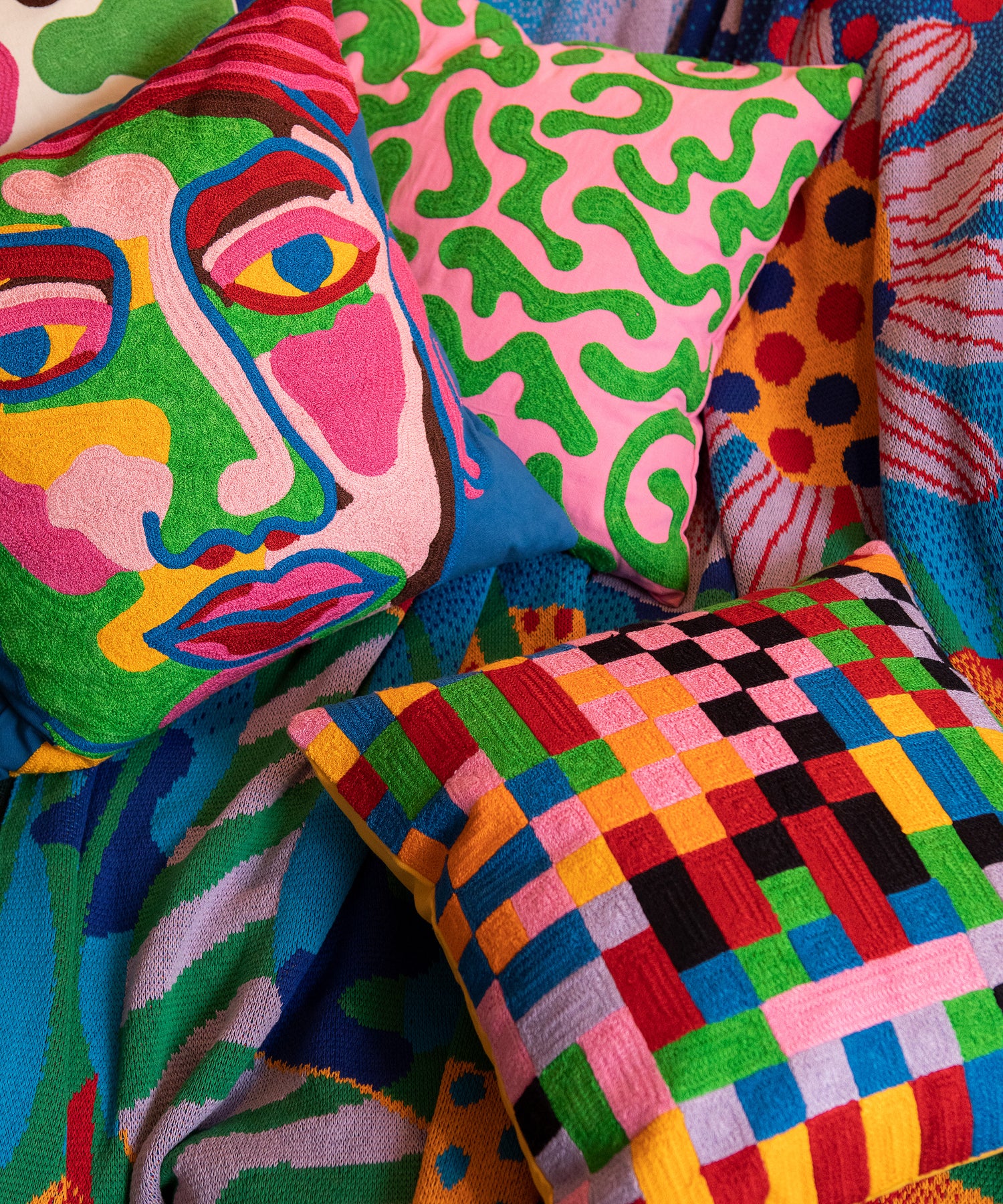 Detail of Portrait Pillow laying on top of the Best Buds Blanket next to the Pixels and Silly Squiggles Pillows.