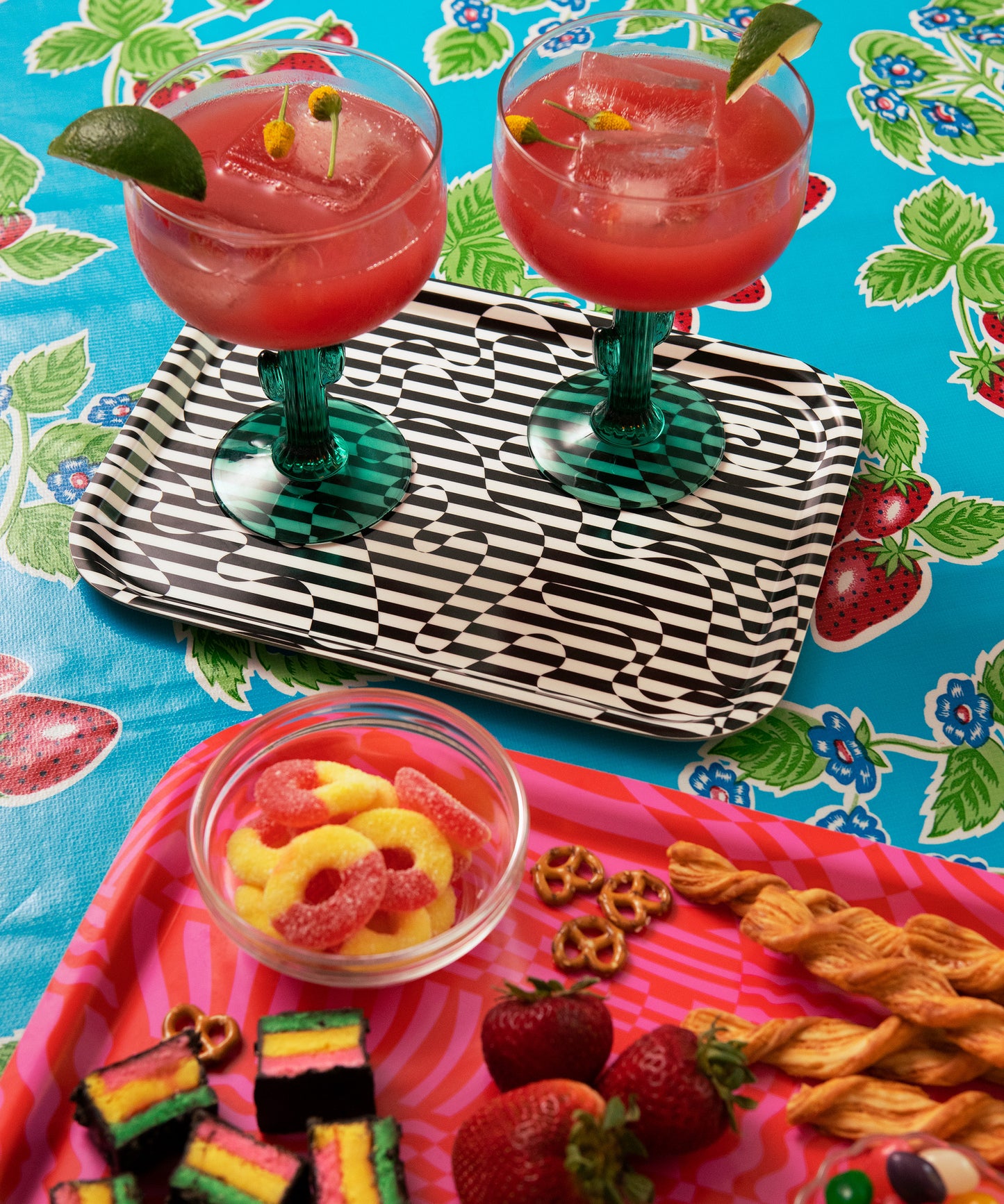 Detail of the Dazzle Tray with two margarita glasses standing on it. Next to the Dazzle Tray is the Wiggles and Waves Tray with cookies, strawberries, and peach rings.