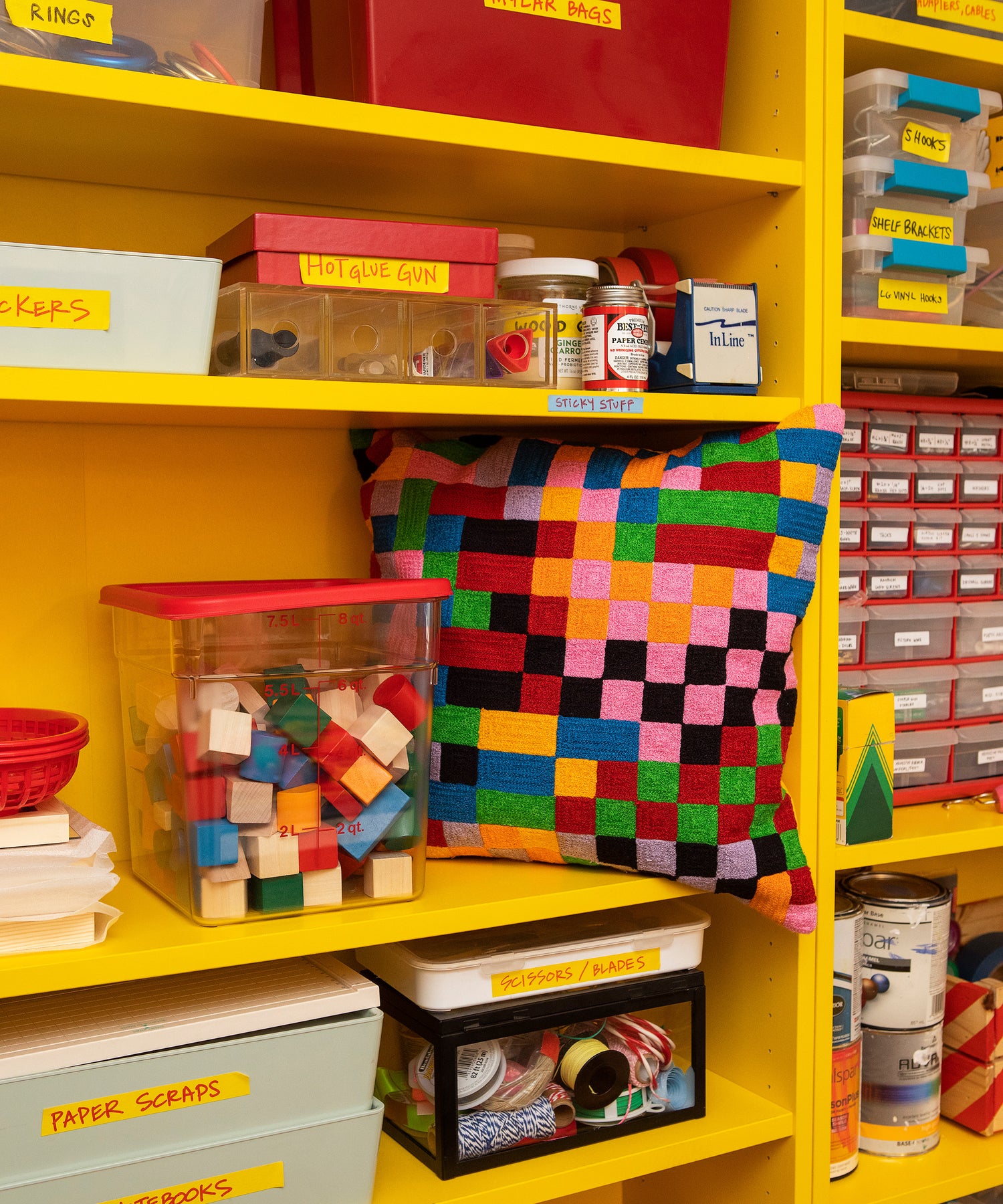 Detail of the Pixels Pillow sitting in a shelf on a yellow bookcase.