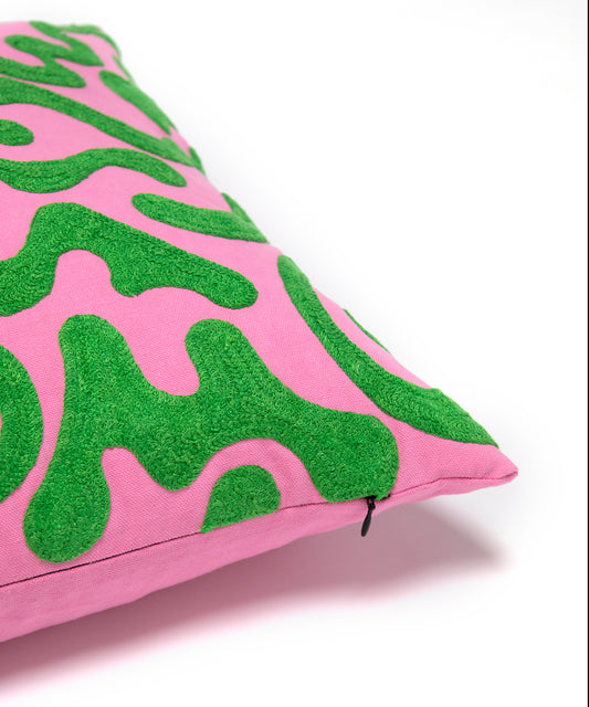 Corner detail of silly squiggle pillow showing green squiggle shapes on it's pink background also showing the zipper enclosure.